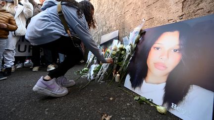 Une adolescente dépose des fleurs devant le lycée Jean-Henri-Lambert de Mulhouse (Haut-Rhin), où était scolarisée Dinah, lors d'une marche blanche le 24 octobre 2021. (FREDERICK FLORIN / AFP)