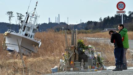 Deux hommes se recueillent pr&egrave;s de la centrale nucl&eacute;aire de Fukushima (Japon), le 11 mars 2014, trois ans apr&egrave;s le s&eacute;isme et le tremblement de terre qui avaient frapp&eacute; le littoral. (YOSHIKAZU TSUNO / AFP)