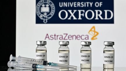 Des seringues et des flacons&nbsp;devant les logos de l'université d'Oxford et de la société pharmaceutique britannique AstraZeneca, le 17 novembre 2020 (image d'illustration). (JUSTIN TALLIS / AFP)