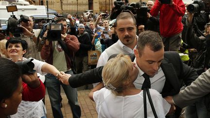 L'athl&egrave;te paralympique Oscar Pistorius est enlac&eacute; par une admiratrice &agrave; son arriv&eacute;e au tribunal de Pretoria (Afrique du Sud), le 14 avril 2014. ( SIPHIWE SIBEKO / REUTERS)