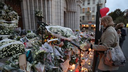 Une femme dépose des fleurs en hommage aux victimes de l'attentat commis à la basilique Notre-Dame de l'Assomption, à Nice, le 31 ocotbre 2020. (VALERY HACHE / AFP)