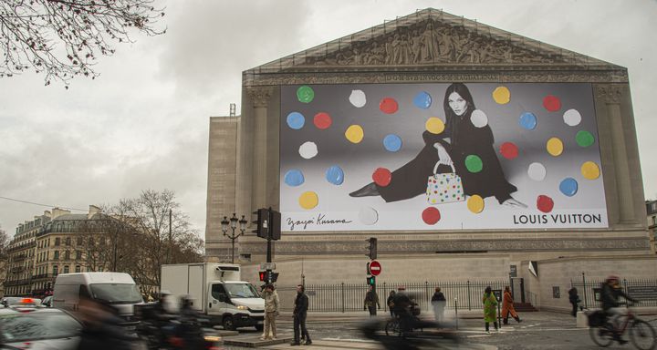 Un panneau publicitaire illustrant la collaboration entre Louis Vuitton et l'artiste contemporain japonais Yayoi Kusama recouvre l'entrée de l'église de la Madeleine en janvier 2023. (JOAO LUIZ BULCAO / HANS LUCAS / AFP)