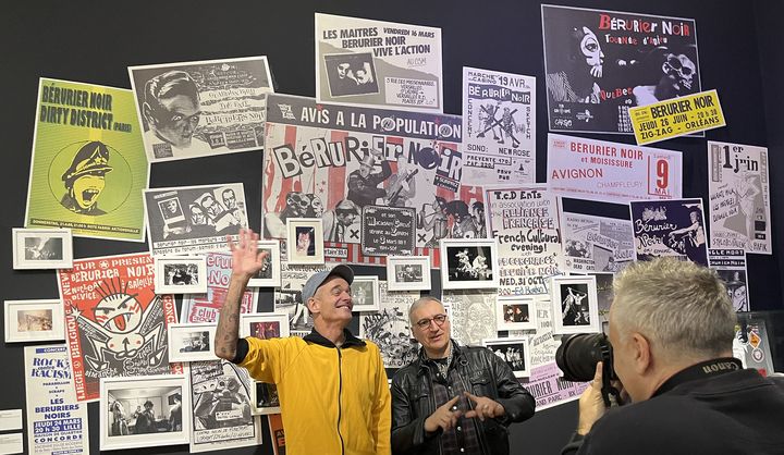 MastO et Fanxoa devant un mur d'affiches et de photos, à l'exposition des archives du fonds Bérurier Noir à la BnF, le 26 février 2024. (LAURE NARLIAN / FRANCEINFO CULTURE)