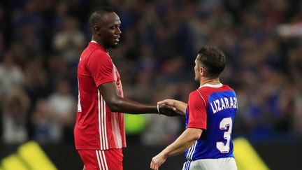 L'ancien sprinteur Usain Bolt serre la main du footballeur retraité Bixente Lizarazu, après un match cartitatif entre les Français champions du monde en 1998 et une sélection internationale, le 12 juin 2018&nbsp;à Nanterre. (GONZALO FUENTES / REUTERS)