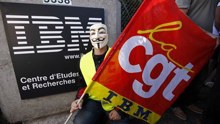 Un salari&eacute; d'IBM, masqu&eacute;, porte un drapeau de la CGT, au centre de recherches IBM de La Gaude (Alpes-Maritimes), le 9 ao&ucirc;t 2012.&nbsp; (ERIC GAILLARD / REUTERS)