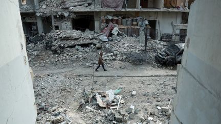 Un Syrien marche dans les rues détruites par les bombardements, à Douma, dans la Ghouta orientale, le 25 février 2018.&nbsp; (HAMZA AL-AJWEH / AFP)