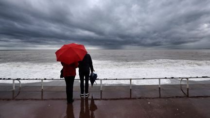 Des touristes face à la mer, sur la promenade des Anglais à Nice (Alpes-Maritimes), le 12 avril 2018. (VALERY HACHE / AFP)