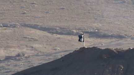 &nbsp; (Un drapeau du groupe terroriste daech-Etat islamique à Kobani, vu depuis la frontière turque ©  REUTERS/Umit Bektas)