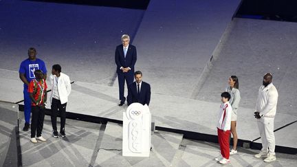 Le président du CIO, Thomas Bach, et le président de Paris 2024, Tony Estanguet, montent sur scène pour tenir un discours de clôture autour de l'amour entre la capitale et ces JO. Ils sont accompagnés par six athlètes représentant les cinq continents et l'équipe des réfugiés. Teddy Riner est présent pour l'Europe. (KMSP / AFP)