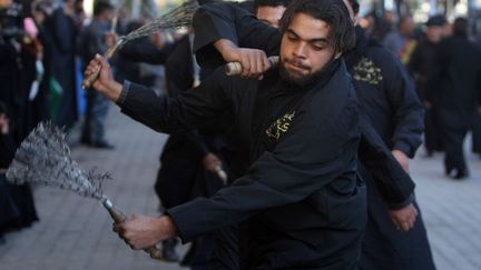 En Irak, les hommes se frappent le dos jusqu'au sang &agrave; l'aide de cha&icirc;nes au son des tambours et des chants religieux. (AHMAD AL-RUBAYE / AFP)