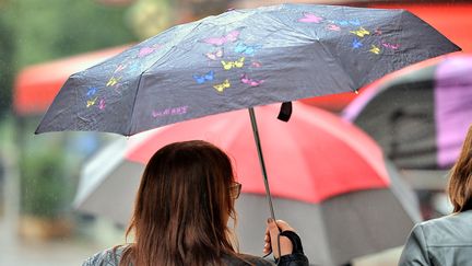 Une piétonne se protège de la pluie, dans une rue de Lille (Nord). (PHILIPPE HUGUEN / AFP)