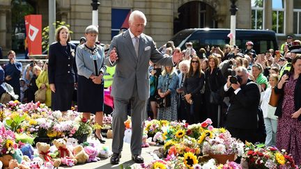 Le roi Charles III réagit en regardant les hommages devant l'hôtel de ville de Southport, le 20 août 2024, lors de sa visite pour rencontrer des membres de la communauté locale, après l'attaque du 29 juillet lors d'une soirée dansante pour enfants. (PETER POWELL / AFP)