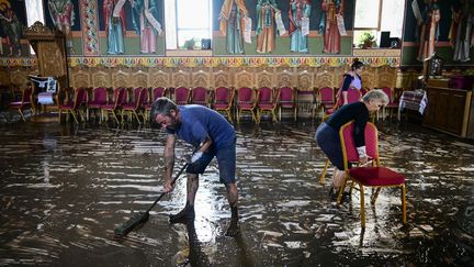 A Pechea (Roumanie), des habitants nettoient le sol de l'église du village, touchée par les inondations, le 15 septembre 2024. (DANIEL MIHAILESCU / AFP)