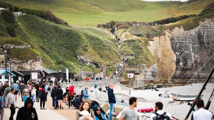 Tourists stroll near the cliffs of Etretat (Seine-Maritime), June 11, 2023. (LOU BENOIST / AFP)