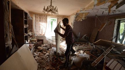 Un homme dans sa maison touch&eacute;e par un obus, &agrave; Gorlovka,&nbsp;dans l'est de l'Ukraine, le 27 juillet 2014. (MIKHAIL VOSKRESENSKIY / RIA NOVOSTI / AFP)