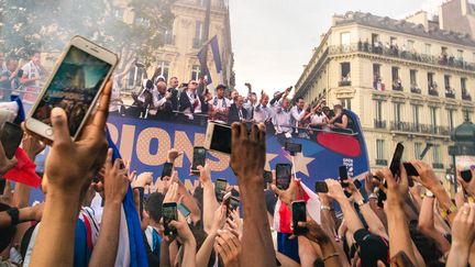 Les fans de l'équipe de France saluent les champions&nbsp;du monde qui défilent sur un bus, à Paris, le 15 juillet 2018. (SIMON GUILLEMIN / HANS LUCAS / AFP)