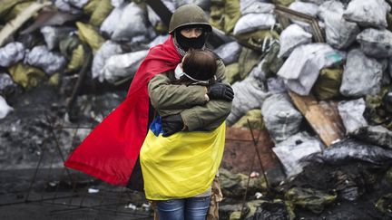 Un manifestant anti-gouvernemental drap&eacute; aux couleurs de l'arm&eacute;e insurrectionnelle ukrainienne (UPA) enlace sa compagne pr&egrave;s d'une barricade &agrave; Kiev (Ukraine), le 10 f&eacute;vrier 2014. (REUTERS)