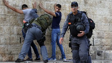 Des policiers isra&eacute;liens fouillent de jeunes Palestiniens, &agrave; l'entr&eacute;e de la vieille ville de J&eacute;rusalem, le 18 octobre 2015. (AHMAD GHARABLI / AFP)