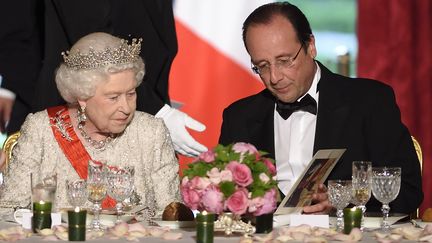 Elisabeth II au dîner officiel à l'Élysée, en 2014, aux côtés du président Hollande. (ERIC FEFERBERG / POOL / AFP)