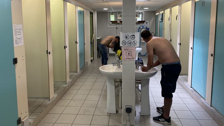 Deux hommes se rafraîchissent dans les bains-douches municipaux Delessert, le 22 août 2023 à Lyon (Rhône). (PAOLO PHILIPPE / FRANCEINFO)