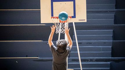 Un écolier&nbsp;fait du basket alors qu'il assiste a différents&nbsp;ateliers au Gymnase Stadium dans le 13e arrondissement de Paris lors des jeux sportifs scolaires, le 4 février 2020. (CHRISTOPHE MORIN / MAXPPP)