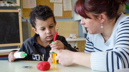 Marjorie Bildstein&nbsp;r&eacute;alise des formes en p&acirc;te &agrave; modeler avec Mohammed, autiste, &agrave;&nbsp;l'&eacute;cole maternelle Ariane Icare de&nbsp;Strasbourg (Bas-Rhin), le 17 mars 2015. (MARIE-VIOLETTE BERNARD / FRANCETV INFO)