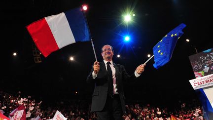 Fran&ccedil;ois Hollande brandit un drapeau fran&ccedil;ais et un drapeau europ&eacute;en, dimanche 29 avril &agrave; Paris-Bercy. (MOUSSE-POOL / SIPA)