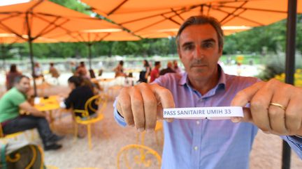 Laurent Tournier, président de l'Union des métiers et des industries de l'Hôtellerie de Gironde, présente le bracelet qui devait être testé&nbsp;dans le département&nbsp;pour éviter la présentation systématique du&nbsp;pass sanitaire. (MEHDI FEDOUACH / AFP)