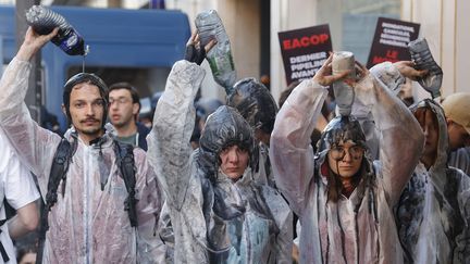 Des militants écologistes ont versé du faux pétrole sur leur tête, lors de la manifestation du 26 mai, dans le cadre de l'AG de TotalEnergies. (GEOFFROY VAN DER HASSELT / AFP)