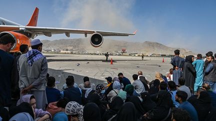 Des Afghans&nbsp;attendent sur&nbsp;le tarmac de l'aéroport de Kaboul pour tenter de fuir le pays, le 16 août 2021. (WAKIL KOHSAR / AFP)