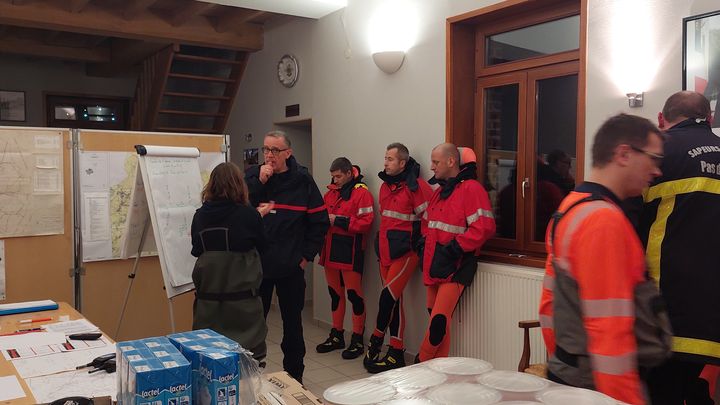 La maire de Bourthes, Estelle Doutriaux (de dos à gauche), en discussion avec les pompiers alors qu'une nouvelle alerte rouge aux crues touche cette petite commune du Pas-de-Calais, le 2 janvier 2024. (FABIEN MAGNENOU / FRANCEINFO)