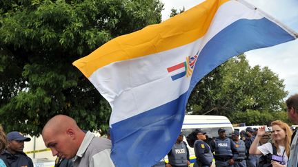 Des sud-Africains soutenant le Mouvement de résistance Afrikaners (AWB), un groupuscule suprémaciste blanc, brandissent le drapeau de l'apartheid devant le tribunal sud-africain de Ventersdorp, le 6 avril 2010.&nbsp; (ALEXANDER JOE / AFP)