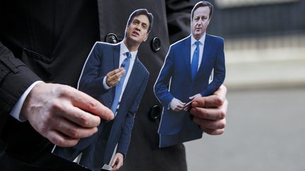 Un pr&eacute;sentateur de t&eacute;l&eacute;vision brandit deux figurines &agrave; l'effigie d'Ed Miliband (G.) et de David Cameron, le 18 mars 2015, &agrave; Londres (Royaume-Uni).&nbsp; (MAXPPP)