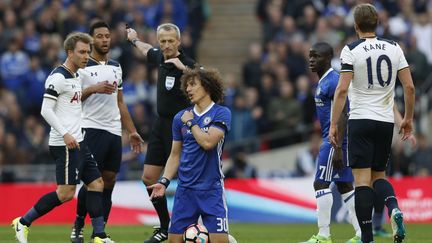 Le Brésilien de Chelsea, David Luiz, à terre face aux joueurs de Tottenham, sous le regard de l'arbitre. (ADRIAN DENNIS / AFP)