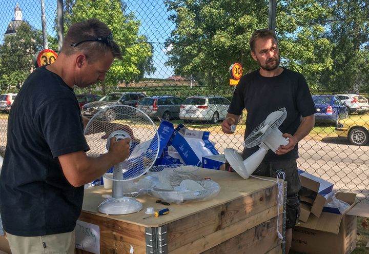 Mikael Wikström et Anders Carlström montent des ventilateurs dans le camp de base pour les pompiers à Färila (Suède), le 24 juillet 2018. (ELISE LAMBERT / FRANCEINFO)