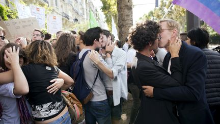 Des couples homosexuels s'embrassent devant l'ambassade de Russie &agrave; Paris, pour protester contre la politique de Vladimir Poutine &agrave; leur encontre, le 8 septembre 2013.&nbsp; (LIONEL BONAVENTURE / AFP)