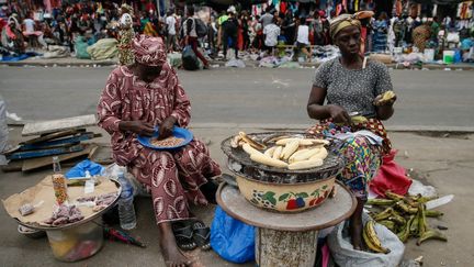 Des femmes vendant de la banane braisée au bord de la route, à Abidjan (Côte d'Ivoire), le 13 août 2019.&nbsp; (MAHMUT SERDAR ALAKUS / ANADOLU AGENCY)