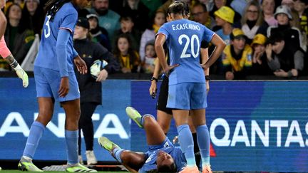 Wendie Renard et Estelle Cascarino autour de Selma Bacha au sol, lors du match entre l'Australie et la France, le 14 juillet 2023. (WILLIAM WEST / AFP)