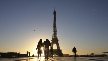 Des touristes près de la tour Eiffel, à Paris, le 14 janvier 2017. (LUDOVIC MARIN / AFP)