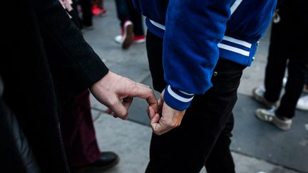 Deux hommes se tiennent la main lors d'une manifestation contre les violences homophobes, à Paris, le 21 octobre 2018. (BENJAMIN MENGELLE / HANS LUCAS / AFP)