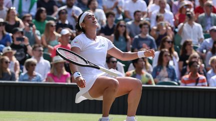 La Tunisienne Ons Jabeur à la renverse sur le gazon de Wimbledon après sa victoire sur Garbine Muguruza, le 2 juillet 2021. (ADRIAN DENNIS / AFP)