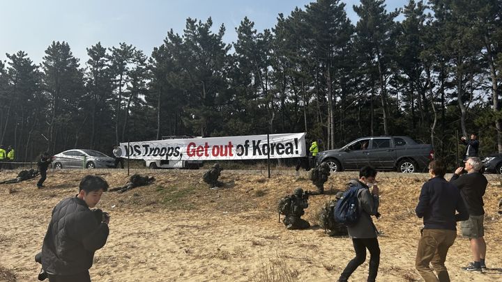 D'un côté de la plage, des manifestants ont déployé une banderole exigeant le départ des troupes américaines de Corée. (NICOLAS ROCCA / RADIO FRANCE)