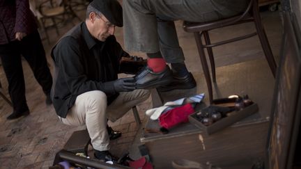 Javier Castano cire les chaussures d'un client, le 16 f&eacute;vrier 2015, &agrave; Malaga (Espagne). (JORGE GUERRERO / AFP)