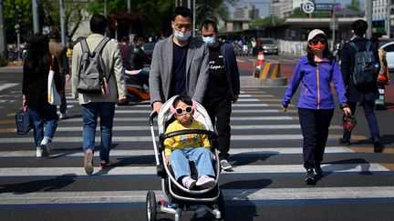 Un homme poussant une poussette traverse une rue à Pékin, le 19 avril 2022. (WANG ZHAO / AFP)