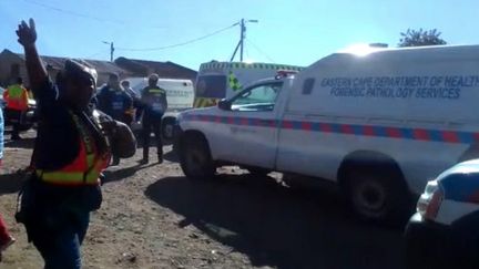 Un officier de police&nbsp;et&nbsp;des véhicules des services de&nbsp;secours stationnés dans un pub du township d'East London, ville du sud de l'Afrique du Sud, le 26 juin 2022. (WANDISWA NTENGENTO / AFP)