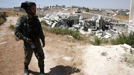 Un soldat devant l'une des maisons détruites, le 22 juillet.&nbsp; (HAZEM BADER / AFP)