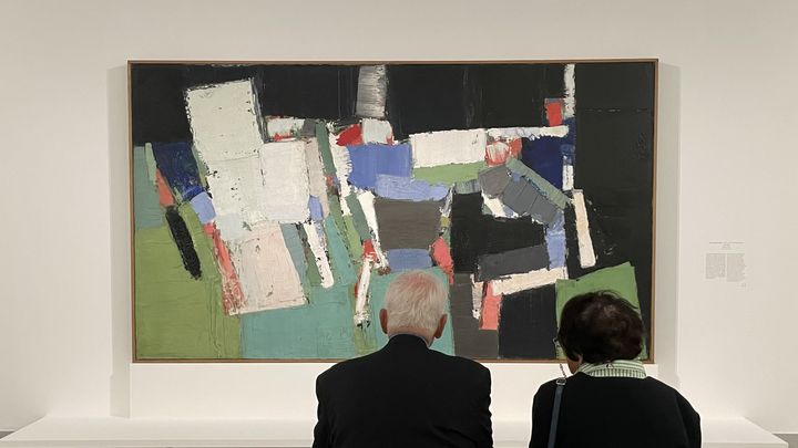 Deux personnes regardent au musée d'Art moderne de Paris "Le Parc des Princes" (1952) de Nicolas de Staël. (FRANCEINFO / NEIL SENOT)