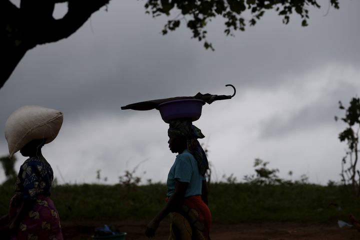 Portant du maïs (et un parapluie)sur la tête, des agricultrices marchent dans la campagne près de Lilongwe, la capitale du Malawi, le 2 février 2016. (REUTERS - MIKE HUTCHINGS / X00388)