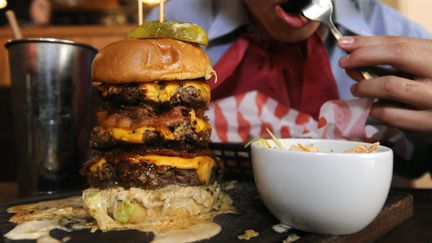 Un client mange un burger g&eacute;ant dans un restaurant londonien, le 4 septembre 2012. (MAXPPP)