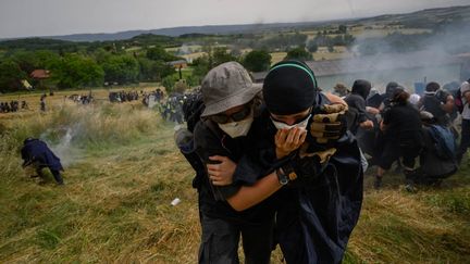 Des manifestants s'éloignent d'une grenade envoyée par les forces de l'ordre lors d'un rassemblement contre le chantier du prolongement de l'autoroute A69 à Puylaurens (Tarn), le 8 juin 2024. (ED JONES / AFP)